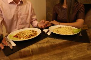 Garda Hotel في لارانجيراس دو سول: يجلس شخصان على طاولة مع طبقين من الطعام