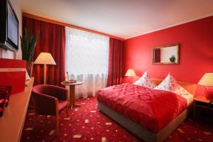 a red bedroom with a bed and a desk and a chair at Hotel Rosenstadt & Malxestube Restaurant in Noßdorf +9 photos