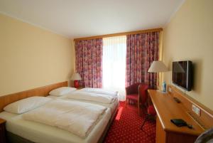 a hotel room with two beds and a desk and a television at Hotel Rosenstadt & Malxestube Restaurant in Noßdorf