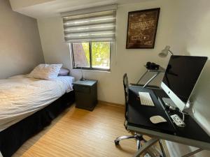 a bedroom with a desk with a computer and a bed at Departamento Delux in Santiago