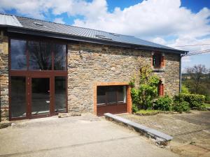 una casa de piedra con garaje y puerta en Gîte Les trois charmes en Gouvy