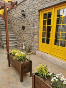 una porta gialla sul lato di una casa con fiori di Ilios Guest House a Gokceada Town