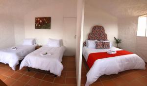 two beds in a room with a red and white bed at Glamping Sierra de Luna in Villa de Leyva