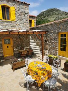 Gokceada Town的住宿－Ilios Guest House，一个带桌椅的庭院和一座建筑