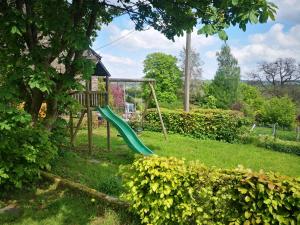 un parque infantil con un tobogán verde en un patio en Gîte Les trois charmes en Gouvy