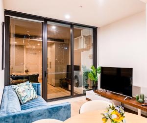 メルボルンにあるStylish Urban Oasisの青いソファとテレビのあるリビングルーム