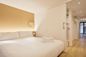 Un dormitorio con una cama blanca con toallas. en Ola Living Vidreria, en Barcelona
