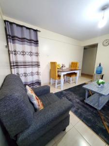 ein Wohnzimmer mit Sofa und Tisch in der Unterkunft 2 BR, TreasureTree Homes, Thika. in Thika