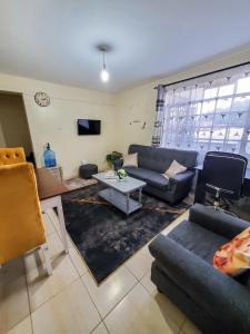 ein Wohnzimmer mit Sofa und Tisch in der Unterkunft 2 BR, TreasureTree Homes, Thika. in Thika