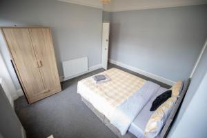 a small bedroom with a bed and a wooden cabinet at The Royalty in Sunderland