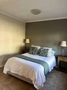 a bedroom with a large white bed with pillows at El Dorado 78 in Oudtshoorn