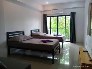 two beds in a room with a window at NK place Phetchaburi in Ban Nong Som