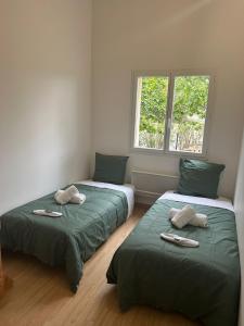 2 camas en una habitación con sábanas verdes y una ventana en Villa au calme avec Piscine Jacuzzi, en Ventenac en Minervois