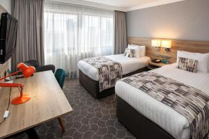 プレストンにあるHoliday Inn Preston, an IHG Hotelのベッド2台とテーブルが備わるホテルルームです。