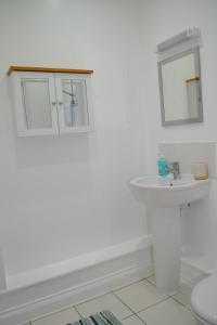 a white bathroom with a sink and a mirror at Beautiful studio in Ely in Ely