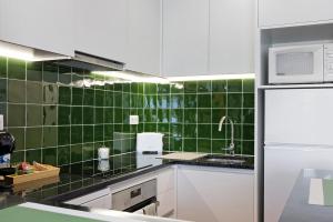 eine grün geflieste Küche mit einer Spüle und einer Mikrowelle in der Unterkunft Casa Vasconcelos in Afife