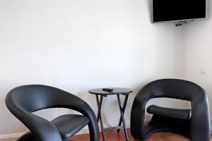 zwei schwarze Stühle neben einem Tisch mit einem TV in der Unterkunft Casa Vasconcelos in Afife