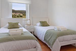2 Betten in einem weißen Zimmer mit Fenster in der Unterkunft Casa Vasconcelos in Afife