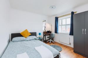 a bedroom with a bed and a desk and a window at The Dahlia Rooms - free parking & wifi in Barking