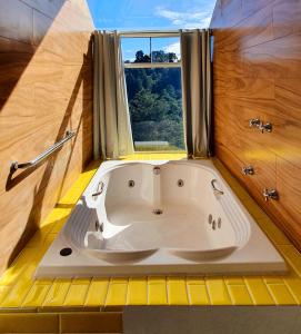 a white bath tub in a bathroom with a window at Golden Forest Pousada in Campos do Jordão