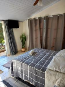 a bedroom with a bed with a blue checked blanket at Pousada Recanto Alegre in Campestre
