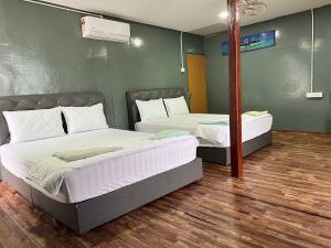 2 Betten befinden sich in einem Zimmer mit Holzböden. in der Unterkunft Khafii House in Kampong Pasir Panjang
