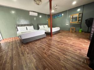 1 Schlafzimmer mit 2 Betten und Holzboden in der Unterkunft Khafii House in Kampong Pasir Panjang
