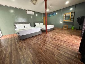 a bedroom with two beds and a wooden floor at Khafii House in Kampong Pasir Panjang