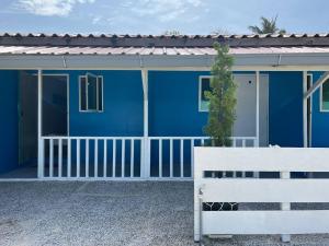 a blue house with a white fence in front of it at Khafii House in Kampong Pasir Panjang