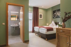 a bedroom with a bed and a bathroom with a sink at Hotel Louis Müller in Bitburg