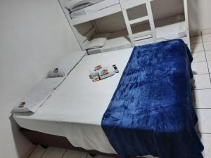 uma cama branca com lençóis azuis e uma escada em Pousada Praia Mongaguá em Frente ao Mar com Piscina e Churrasqueira em Mongaguá