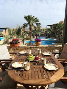 una mesa de madera con comida y vistas a la piscina en Ninas Place, 5min On Foot From The Beach, en Panormos Rethymno