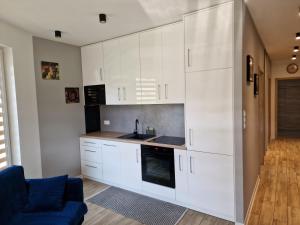 uma cozinha com armários brancos e um sofá azul em Apartament Luxory em Przemyśl