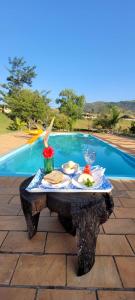 uma mesa com comida ao lado de uma piscina em Pousada Chales da Canastra em Vargem Bonita