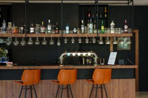 um bar com bancos de bar laranja e garrafas de álcool em Hotel Les Jardins De La Molignée em Dinant