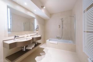 a bathroom with a sink and a tub and a mirror at Hotel Les Jardins De La Molignée in Dinant +41 photos