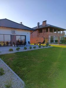 une maison avec une cour dotée d'une terrasse et d'une pelouse dans l'établissement Vikendica Krcmarice- Banja Luka, à Banja Luka
