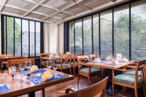 a restaurant with wooden tables and chairs and windows at Offenburg City Hotel by Belvilla in Offenburg