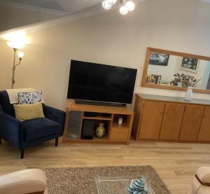uma sala de estar com uma televisão de ecrã plano e uma cadeira em Moniz Apartment no Caniço