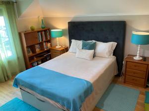 a bedroom with a bed with a blue headboard and two lamps at Moniz Apartment in Caniço