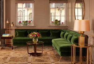 a living room with a green couch and two tables at Flemings Mayfair - Small Luxury Hotel of the World in London