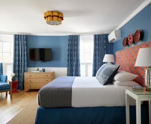 1 dormitorio con paredes azules, 1 cama y TV en The Christopher, The Edgartown Collection, en Edgartown