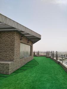 Sayhātにあるفندق ايلاف الشرقية 2 Elaf Eastern Hotel 2の柵の横に緑の芝生がある建物