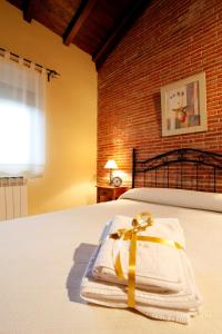 Una cama con una toalla con un arco. en Casa Rural Puerta del Sol de 3 habitaciones, en Candelario