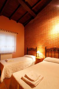 1 dormitorio con 2 camas y pared de ladrillo en Casa Rural Puerta del Sol de 3 habitaciones en Candelario