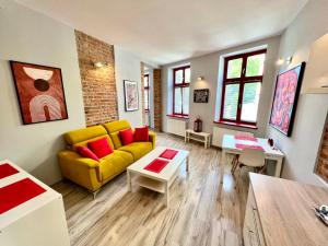 a living room with a yellow couch and red pillows at Red&Yellow Apartments Centrum in Olsztyn