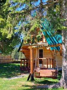a log cabin with a porch and a swing at Cottage Uskoci in Žabljak