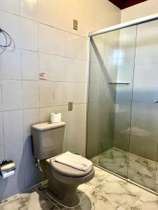 a bathroom with a toilet and a glass shower at Pousada Marques in Paraty