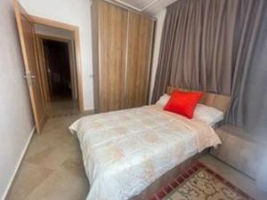 Un dormitorio con una cama con una almohada roja. en Superbe appartement en bord de mer , banana beach, en Aourir