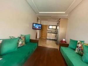 sala de estar con sofá verde y TV de pantalla plana en Superbe appartement en bord de mer , banana beach, en Aourir